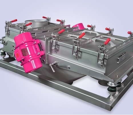 Industrielle Siebmaschine mit roten Verschlusshaken und einem rosafarbenen Kompressor dazwischen.