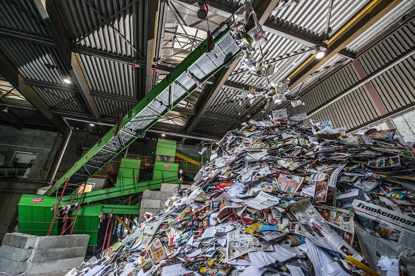 Recyclinghalle Papier wird von einem Förderband auf einen kegelförmigen Haufen transportiert