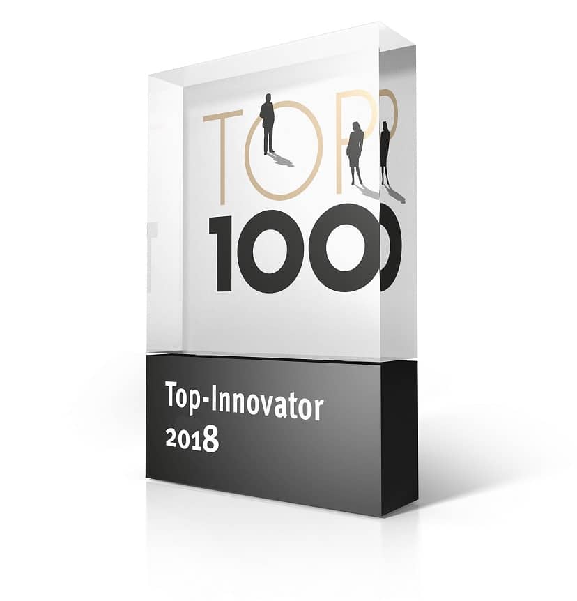 Trophäe aus Glas und Metall. Darauf steht oben hinter Glas Top 100 mit stilisierten Personen darauf. darunter in Weiß auf schwarzem Grund Top-Innovater 2018
