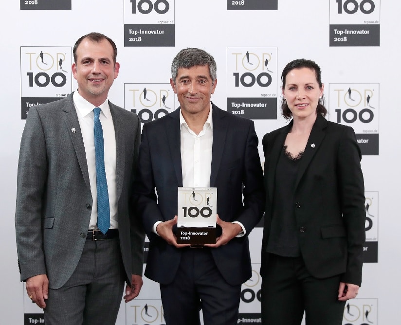 Von links nach rechts Matthias Veith, Ranga Yogeshwar und Isabel Grieshabervor einer Wand mit lauter TOP 100 Top-Innovator 2018 Logos in schwarz auf weißem Grund