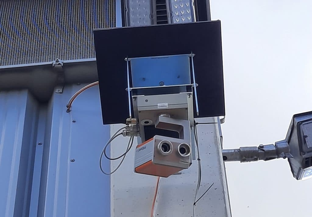 Brandfrühschutzerkennungs Infrarot Kamera an einer Industriehallenwand im Außenbereich angebracht.