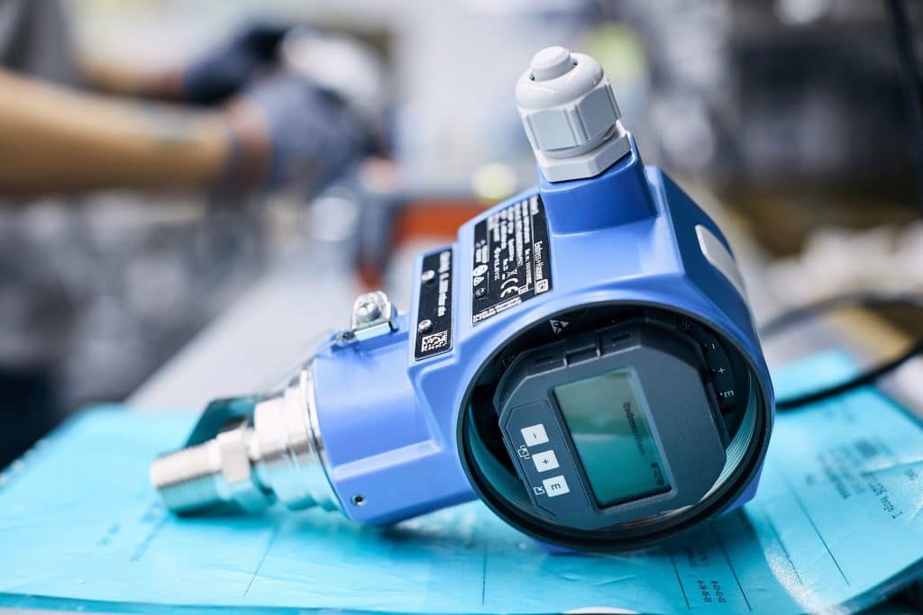 E+H auf Wachstumskurs Messgerät der Endress+Hauser Gruppe auf Unterlagen in blauer Klarsichthülle