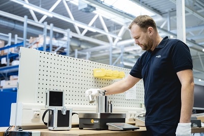 Mitarbeiter der Minebea kontrolliert mit Gewichten eine Waage, auf schuettgutmagazin.de