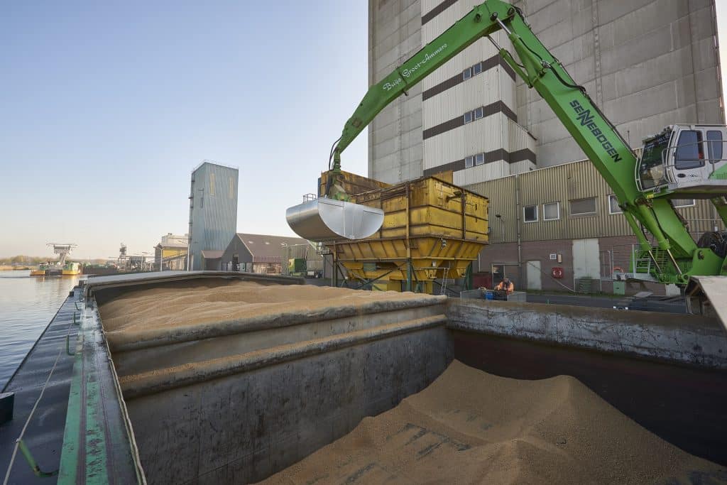 Schiff, das mit einem Bagger entleert wird