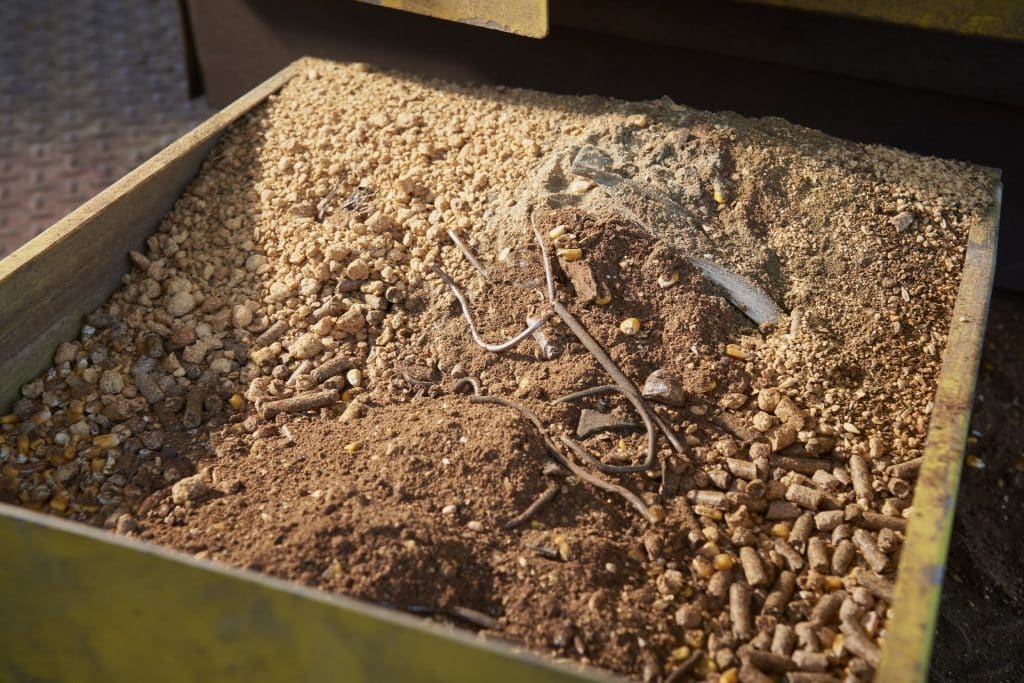 Erde mit Metallstück in einer Schütte, auf schuettgutmagazin.de