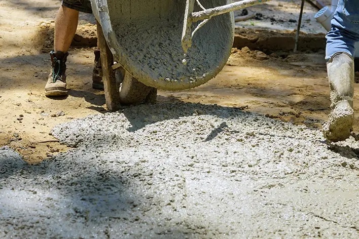 Schubkarre mit Zement, Zement auf dem Boden und Gummistiefel der Arbeiter auf schuettgutmagazin.de