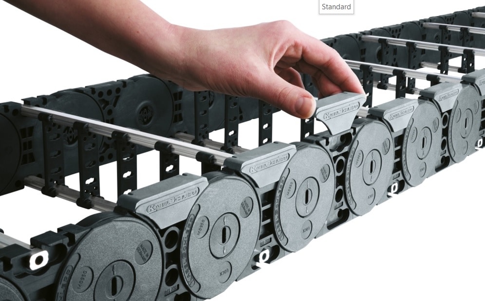 Energieführungskette in das eine Hand ein Element einfügt, damit an dieser Stelle nicht flexibel ist, auf schuettgutmagazin.de