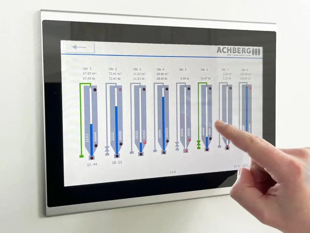 Tablet in Haltevorrichtung an einer Wand mit acht überwachten Silos, die unterschiedliche Füllstände aufweisen.