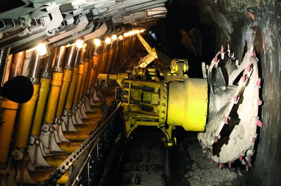 Schneidewalze in einem Steinkohle-Bergbau mit explosionsgeschützten Absolutwertgebern. Rechts die Schneidewalze die an einem gelben Antrieb befestigt ist. Links eine Führungskette und eine beleuchtete Haltekonstruktion.
