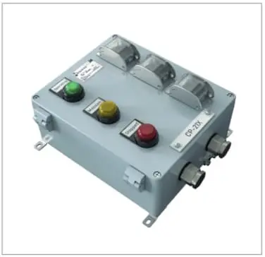 Control Station für den Ex-Schutz. Grauer Metallkasten, leicht rechteckig. Zur Steuerung ein durch eine Kappe geschützter Schalter mit Lichtsignal, von oben nach unten: Grün für Operating, gelb für Maintanance, rot für stopped. An der schmalen Vorderseite befinden sich Steckverbindungen. Auf den langen Seiten Befestigungsschraublöcher und links auch Öffnungsscharniere