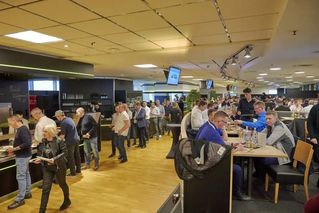 Loge des BVB mit dem Buffet und Schlange der Teilnehmer des Ausstellerabends. Rechts Aussteller, die an Tischen sitzen.