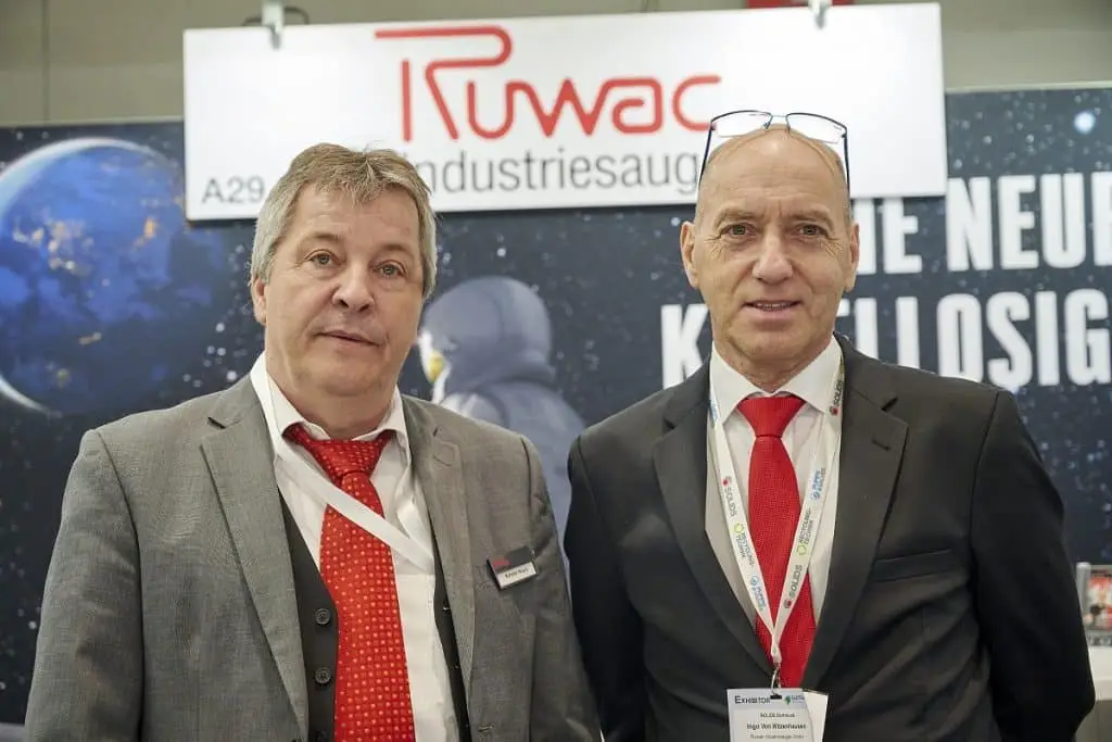 Kasten Noak und Ingo von Witzenhausen der Ruwac vor der Messewand ihres Standes auf der Solids 2023