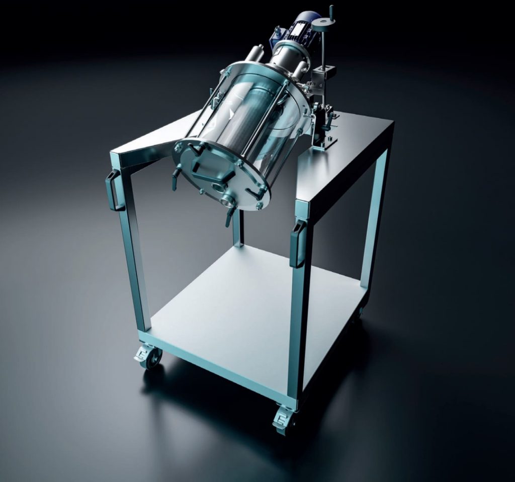 Auf einem Rolltisch, dessen oberes Blech konisch ausgeschnitten ist, ist eine Siebmaschine von assonic fixiert. Durchsichtiger zylindrischer Glasbehälter mit siebartigem Gewebe in der Mitte.