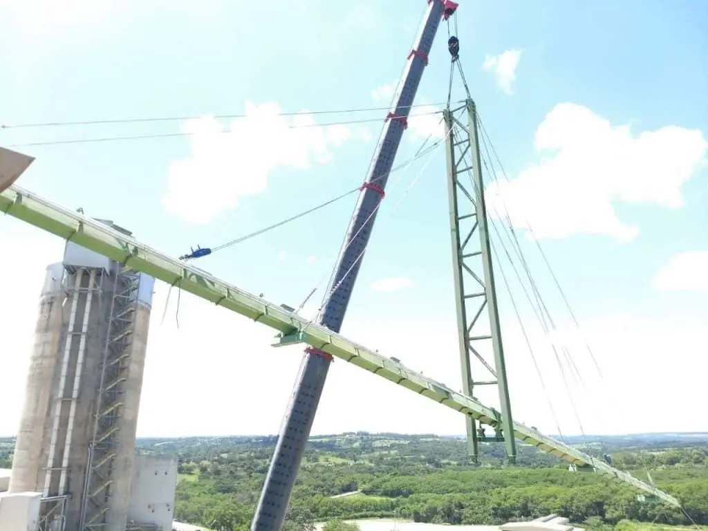 Luftunterstütztests Förderband, das durch ein leiterartiges Gestänge gehalten wird und im Hintergrund ein Silo und Landschaft.