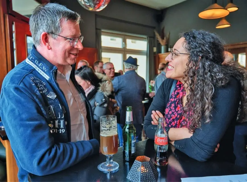 Links Jörg Heyming, von Rosa, rechts Marianny Eisenhofer unterhalten sich an einem Stehtisch beim Kick-off des DSIVs in Dortmund. Im Hintergrund andere Teilnehmer.