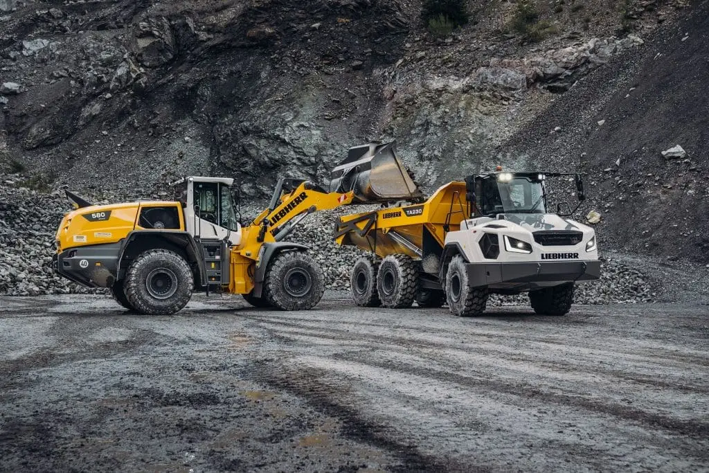 Lieber Erdbewegungsmaschinen, Radbagger und Lastwagen in einem Steinbruch mit dunklem Gestein