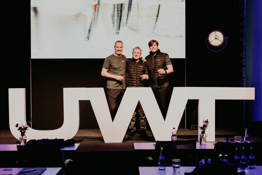 Auf einer Bühne, hinter übergroßen weißen Buchstaben UWT stehen Geschäftsführer v.l.n.r. Uwe Niekrawietz, Andreas Haug, Markus Schalk enthüllen die neue Brand
