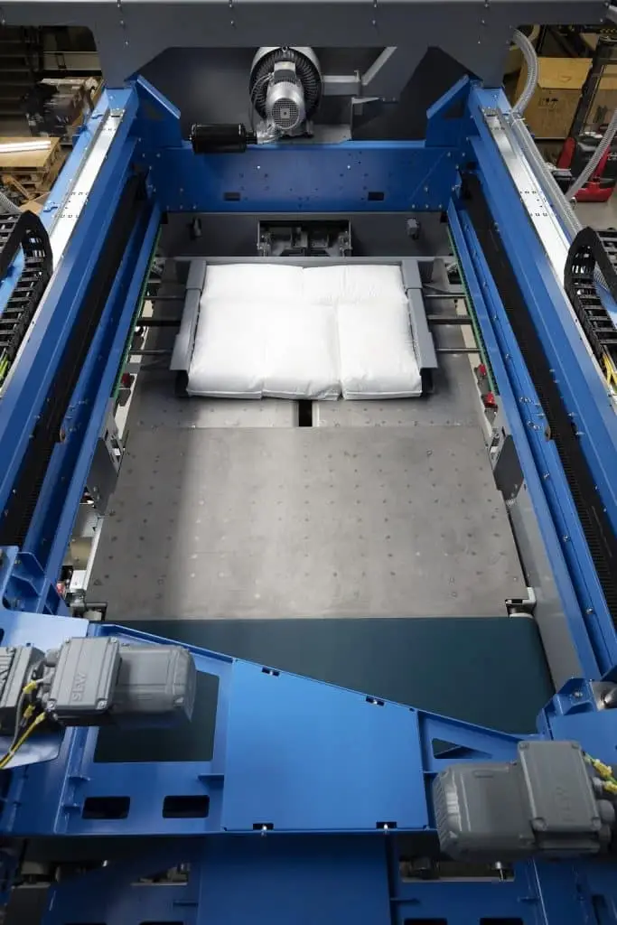 Packmaschine paletpac. In der Mittel liegt ein Produkt das verpackt wurde rechts und links vom Paket Schieber darunter viel Platz für ein größeres Produkt. Darüber Kabelschlepper ,die die Mechanik der Packmaschine mitmachen.