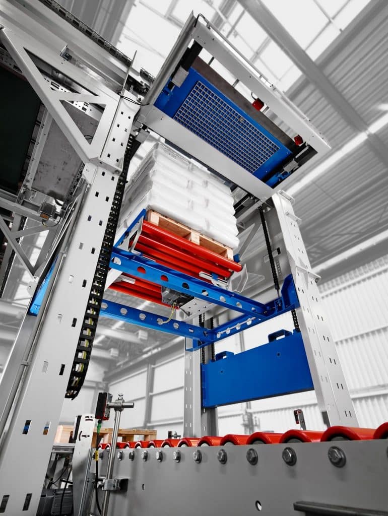 Verpackungsmaschine mit einer Palette, die über einem Roll-Förderband zu sehen ist.