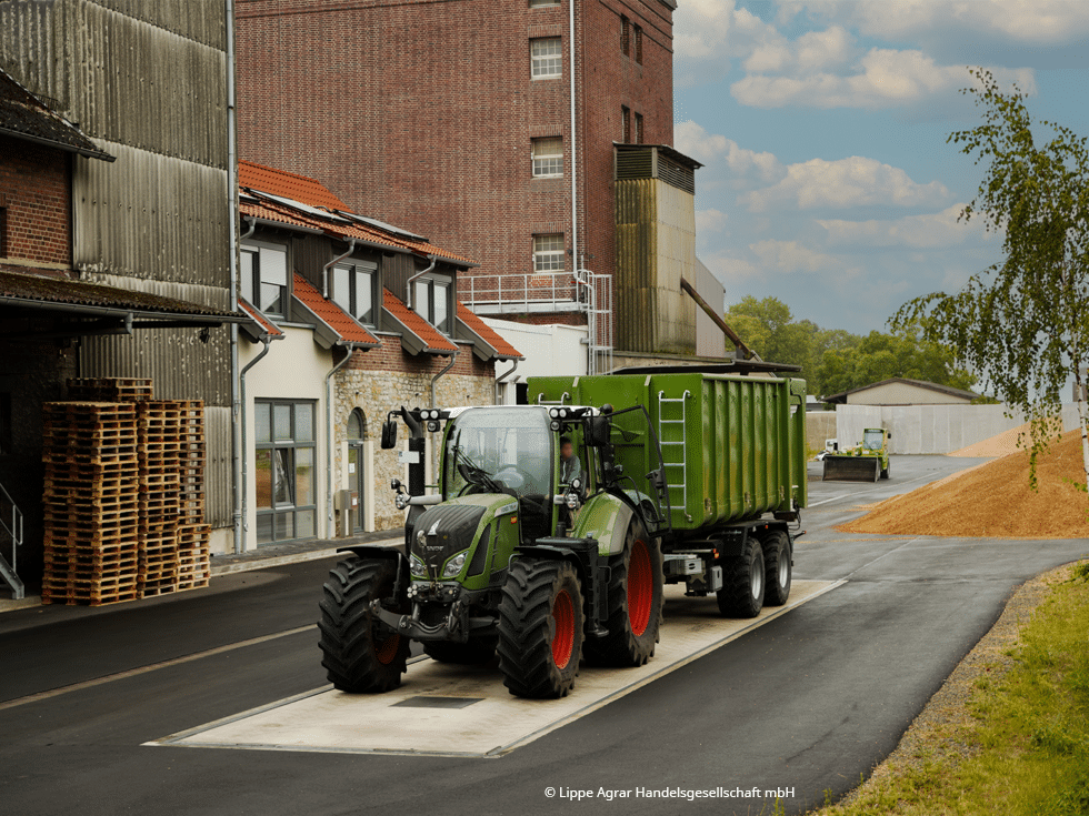 Grüner Traktor auf einer Bodenwaage auf dem Hof eines Getreidehandels