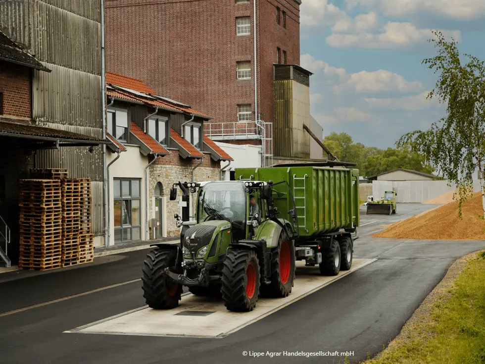 Grüner Traktor auf einer Bodenwaage auf dem Hof eines Getreidehandels