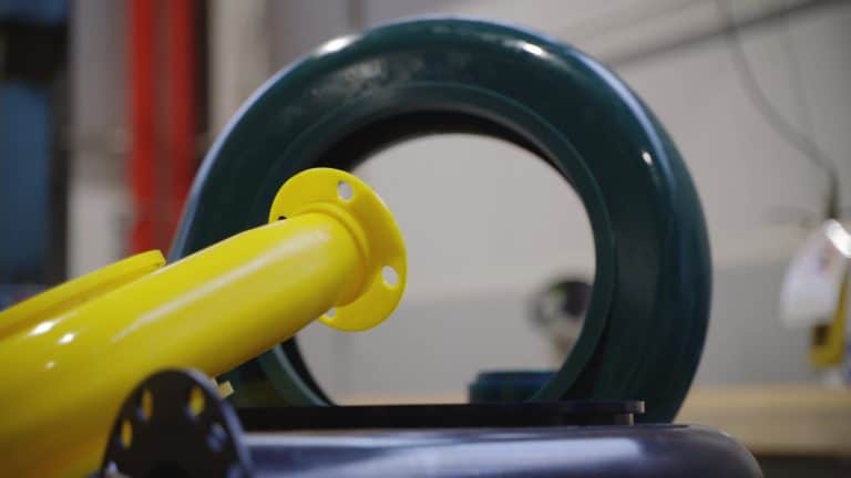 PU Teil für den industriellen Pumpenbetrieb. Im Hintergrund ein Reifen ähnliches Element. Davor ein gelbes Plastikelement, das an eine Tischbeinverschraubung des Tischbeins erinnert.