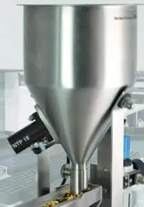 Ein Stahlzylinder mit einem Klopfer NTP 18 über einer Vibrationsrinne als Messemodell.