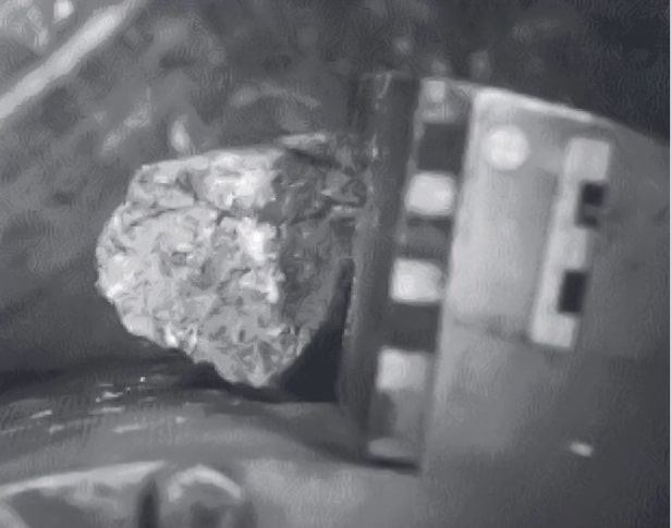 Schwarz-weißes Foto eines Stoßvorgangs. Ein Partikel zwischen den Backen eines Brechers