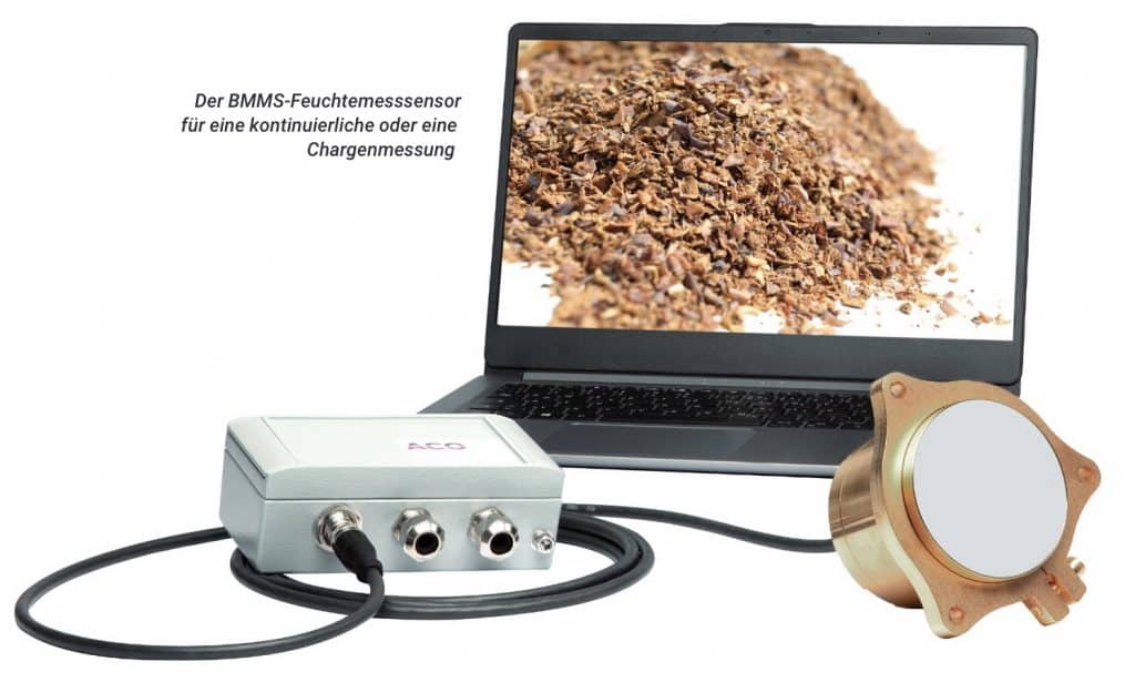 BBMS-Feuchtemessensor, im Hintergrund ein Laptop mit einem Bild von Tabak, davor rechts ein goldener Sensor mit einer weißen Sensorfläche und links ein Adapter mit drei Eingängen.