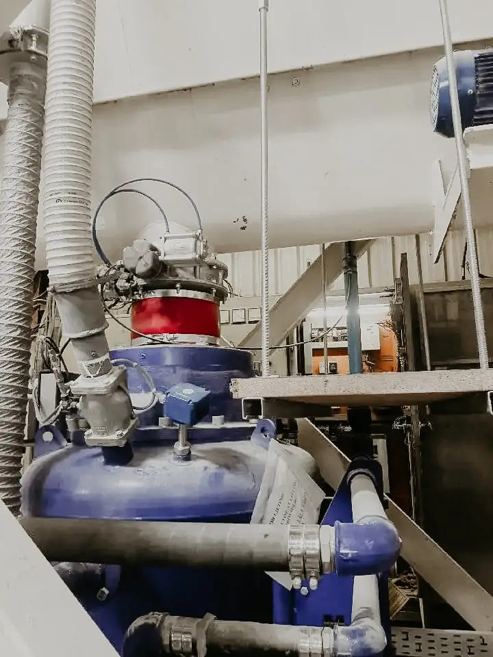 Druckbehälter mit Rohren und Abluftschläuchen in einer staubigen Industriehalle