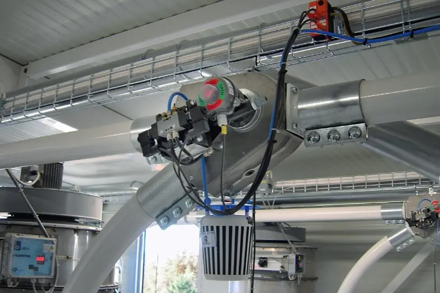 Zwei Rohre, die von links kommend oben rechts in einer Rohrweiche zusammengeführt werden. Man sieht auch Kabel und andere industrielle Gegenstände und Rohre im Hintergrund