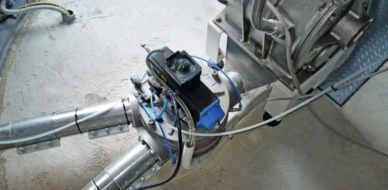 Auf dem Boden einer Industriehalle sind von links kommend zwei Rohre durch eine Trommelrohrweiche verbunden und führen von dort in eine Apparatur.