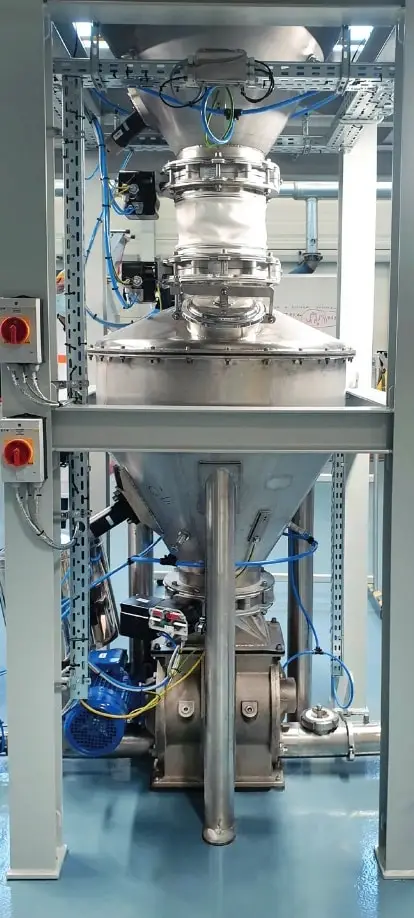 Von oben wird ein Silo mit entleert. Das Entleerungsorgan führt in eine Zellenradschleuse, die das Produkt portioniert in ein weiteres Rohr leitet.