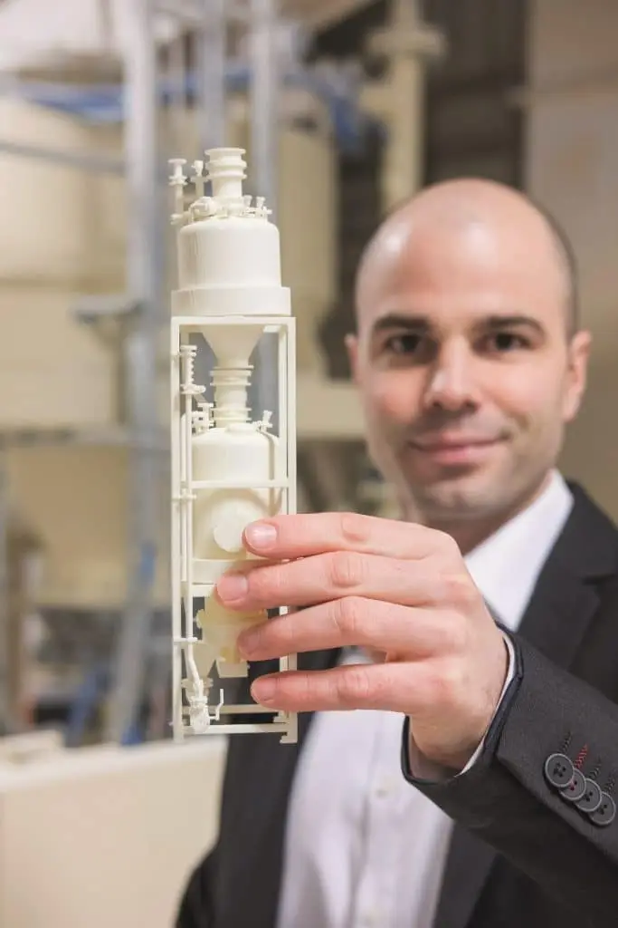 Robert Partzsch, mit einem Modell einer Förderanlage in einer Industriehalle.