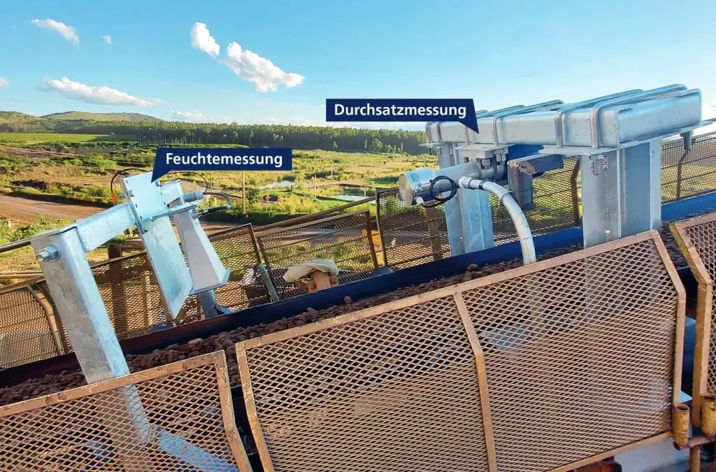 Förderband im Außengelände mit zwei verschiedenen Messstationen. Rechts die Durchsatzmessung, links die Feuchtemessung.