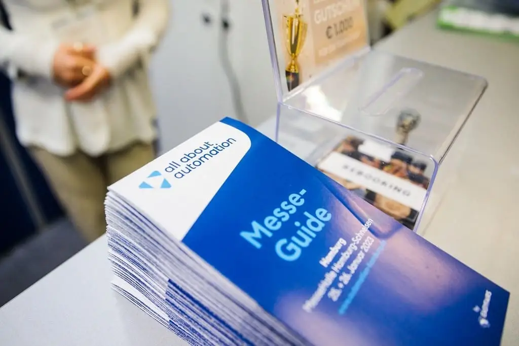 Messeguide der all about automation - kleines rechteckiger mehrseitiger Flyer in blau-weiß.