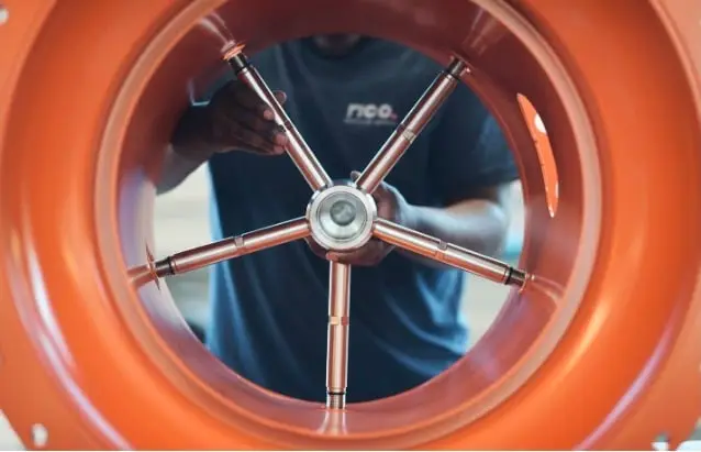 Orangenes Rohr mit einem Metallgestänge, das eine Art Achse bildet. 5 Streben und mittig ein rundes Element