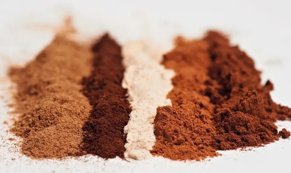 Verschiedenfarbige Pulver -von links nach rechts vielleicht Instant-Zichorien-Kaffee, Espresso, Milchpulver, Curry, Filterkaffee