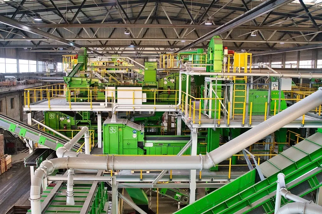 Industriehalle mit drei Etagen, Förderbändern und Sortieranlagen. Alles in grün, stahl und gelb gehalten.