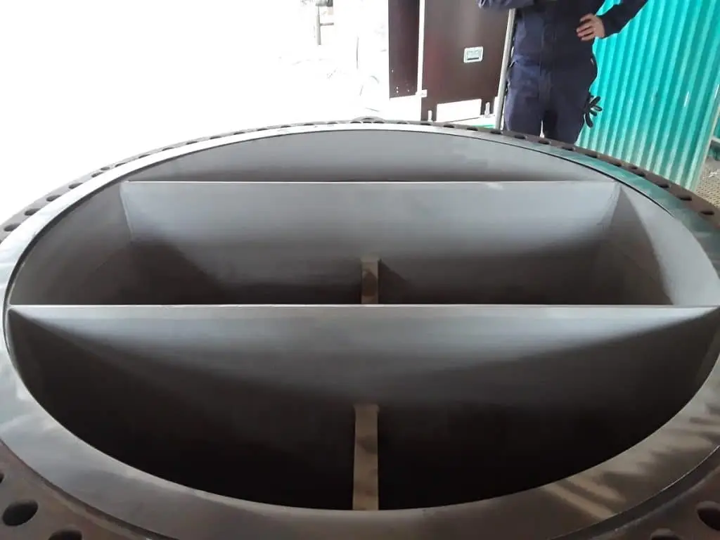 Tiefes Rohr mit durchkreuzenden Platten, die durch einen Metallbalken in der Mitte stabilisiert werden. Um das Rohr liegt ein Metallband mit Löchern.