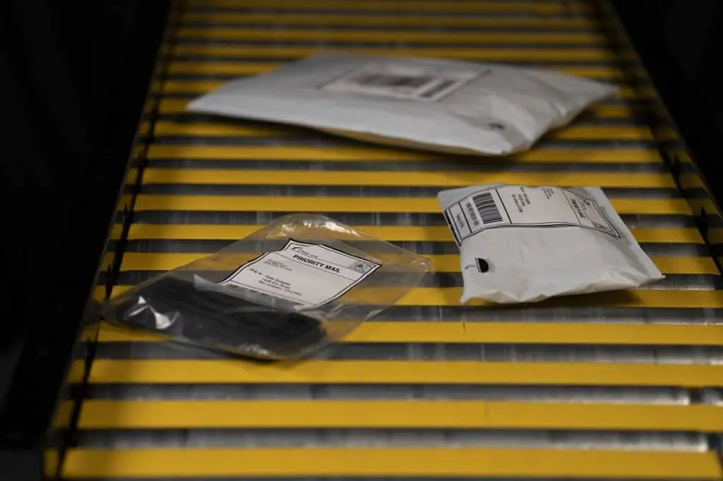 Transportband auf dem kleine in Plastik verpackte, mit Label versehene Päckchen liegen. RCPs decken die Förderbandrollen ab, sodass die Päckchen nicht in die Rollenzwischenräume fallen können