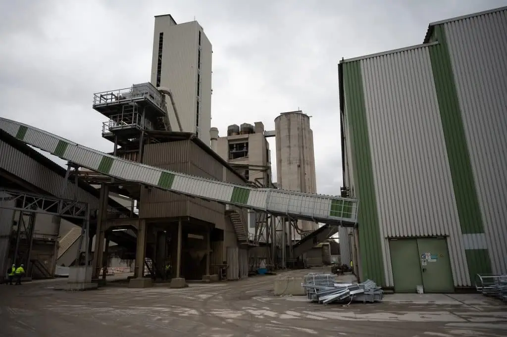 Zementwerk Hof und im Hintergrund runde zwei Silos, rechts daneben ein Turm, davor überdachte Förderbänder und rechts eine Industriehalle.