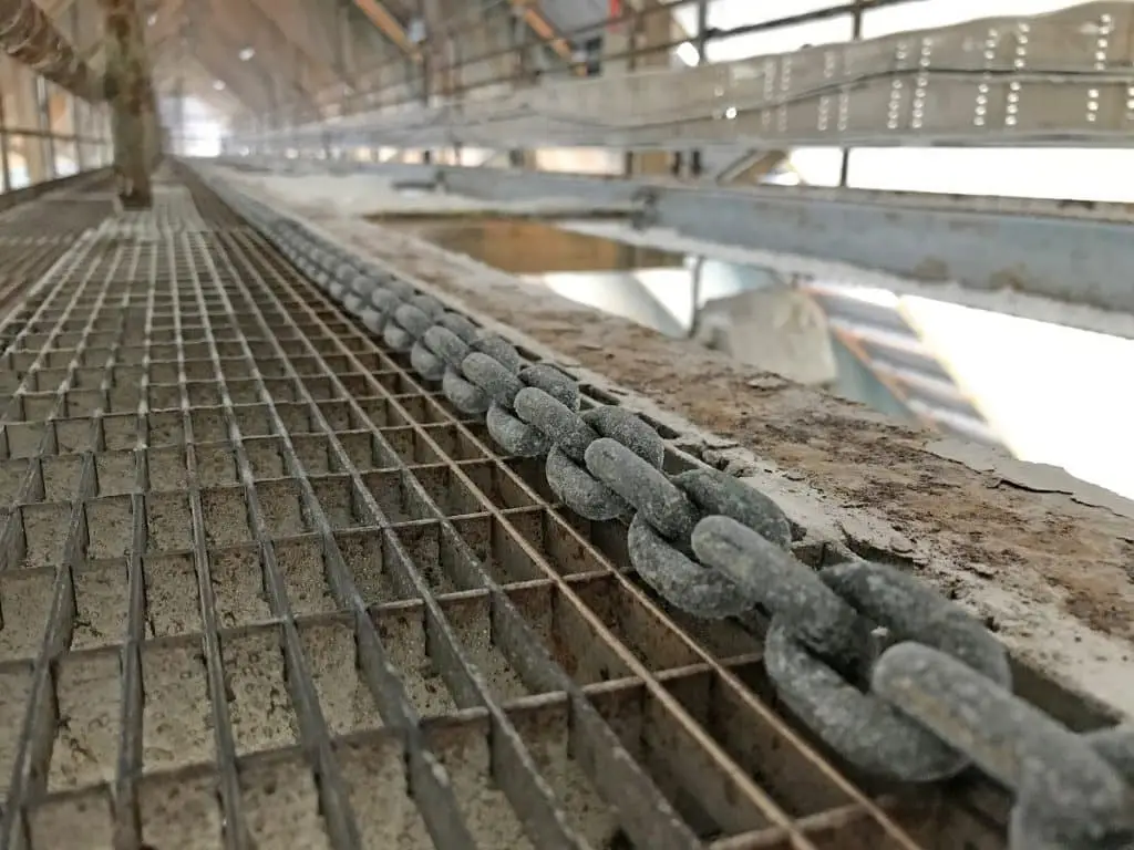 Förderkette neben Metallgittersteg. Viel Salz und Staub sind auf der Kette zu sehen.