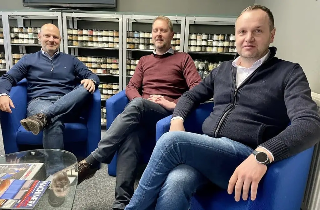 Jan Pohl, Marc Le Meut & Andrzej Maj sitzen vor einem Sideboard mit enorm vielen Schüttgutproben in kleinen Gläsern