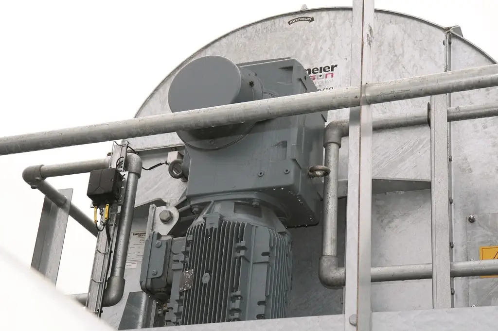 Getriebemotor der draußen an einem Getreideterminal angebaut ist. Man sieht Aluwände,Rohre und Geländer und den dunkelgrauen Getriebemotor.