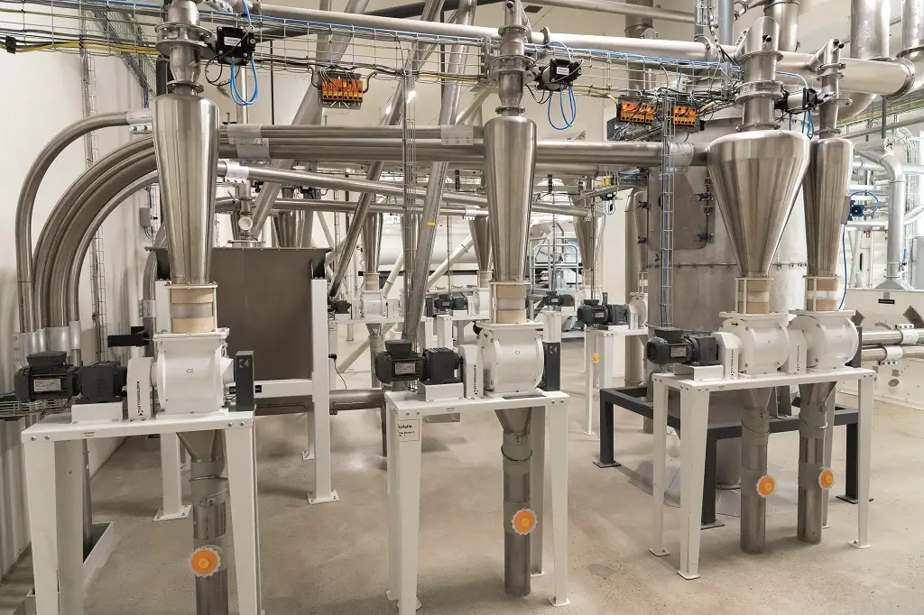 Innenraum einer modernen Mühle mit Rohren und Verbindungen. Stahl und weiß gestrichene Metallgegenstände