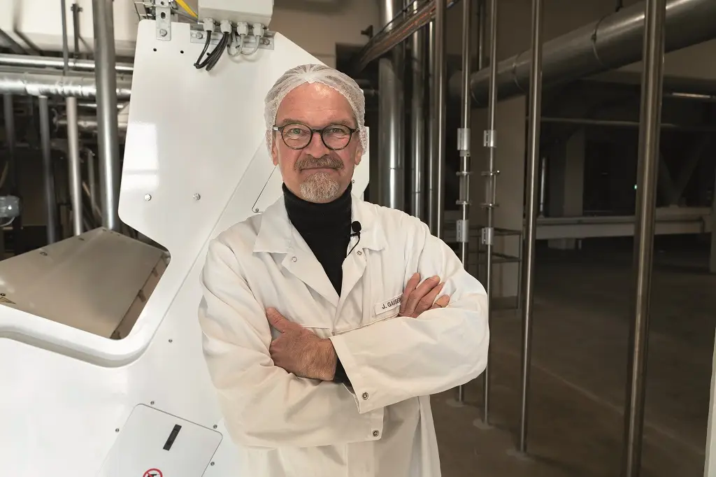 Jan Gausepohl in weißer Kleidung mit Haarnetz in Industriegebäude