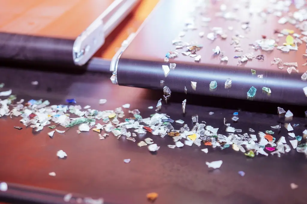 Drei Laufbänder sind zu sehen. Eines ist unterhalb zweier anderer. Deren Ende ist sichtbar. Das Linke ist leer, das rechte hat kleine bunte Glasscherben auf dem Band und wirft es auf eine darunter laufende Laufbandfläche.