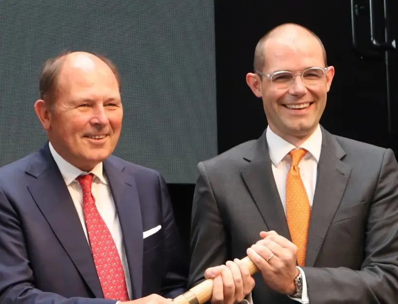 Dr. Hans Moormann und Alexander Moormann, die einen Staffelstab untereinander übergeben