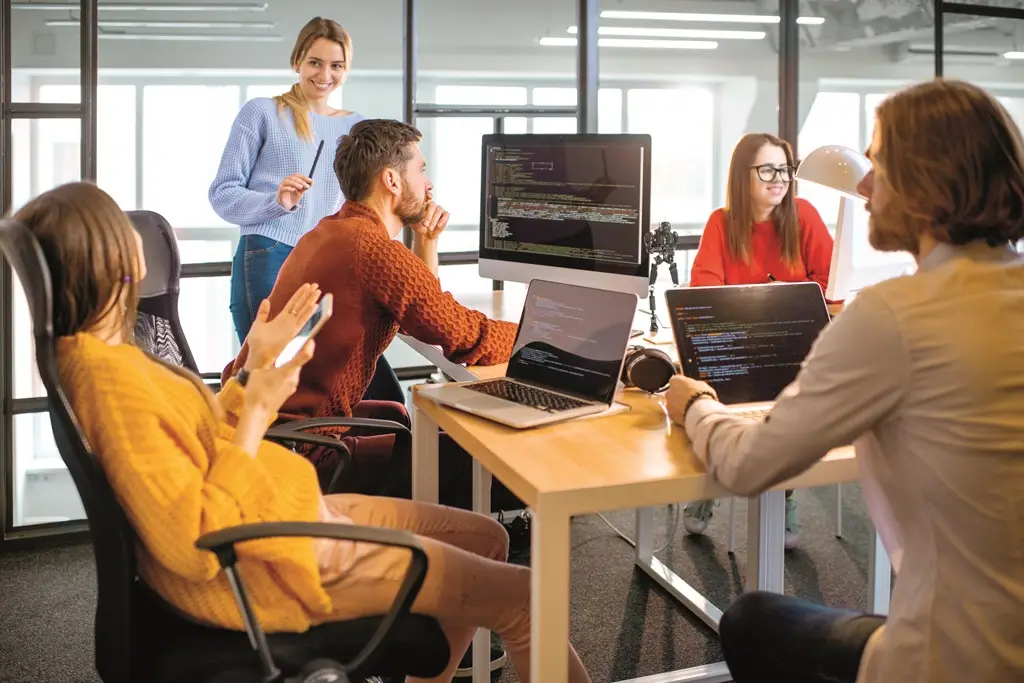 Team of a young programmers dressed casually working on computer code sitting in the modern office interior